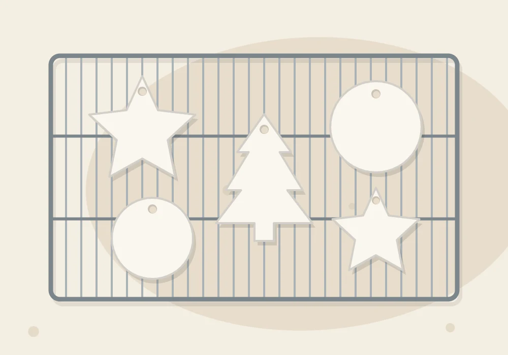 Star, tree and circle ornaments with hanging holes drying on a wire rack, seen from above