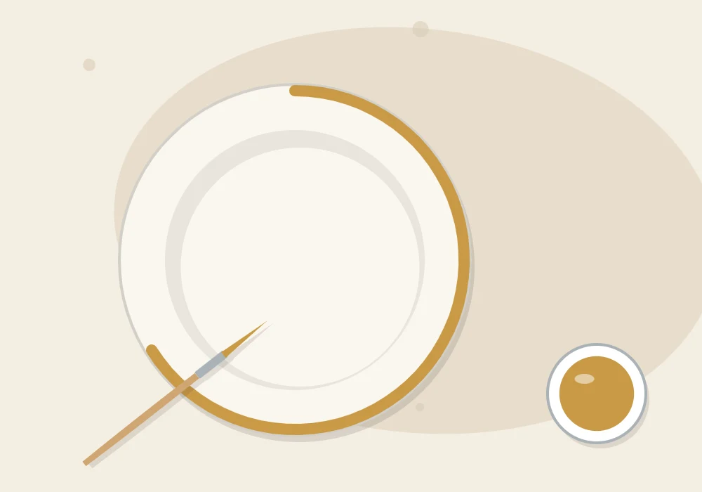 A fine detail brush painting a mustard-gold line around the rim of a dry white clay dish