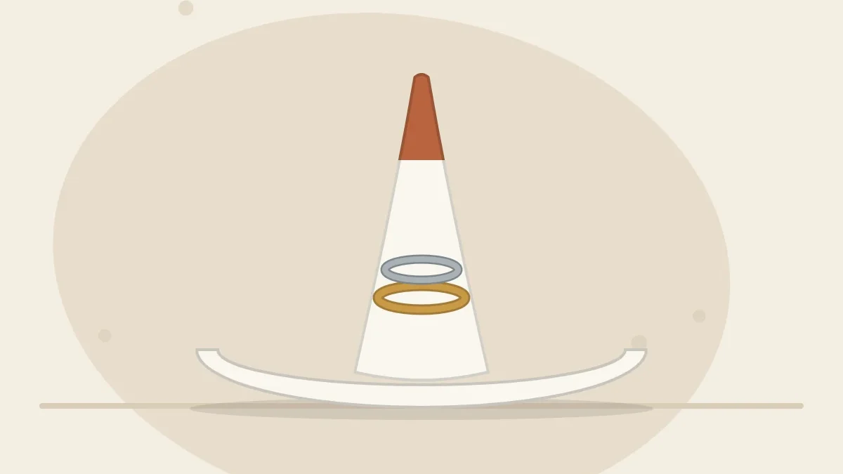 A clay ring holder: a white cone with a terracotta tip standing in the center of a small round dish, two rings stacked on the cone