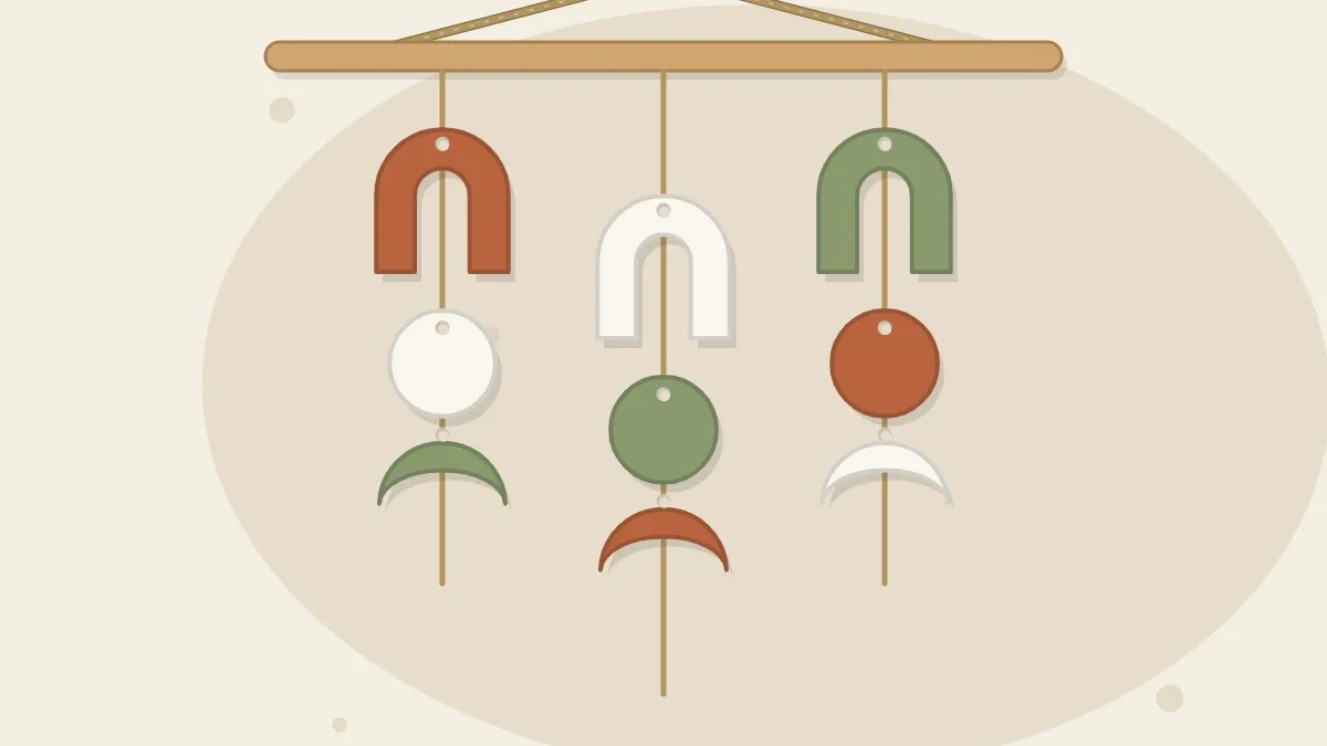 A wall hanging made of a wooden dowel with three strands of twine holding clay arches, circles and crescent shapes in terracotta, white and sage