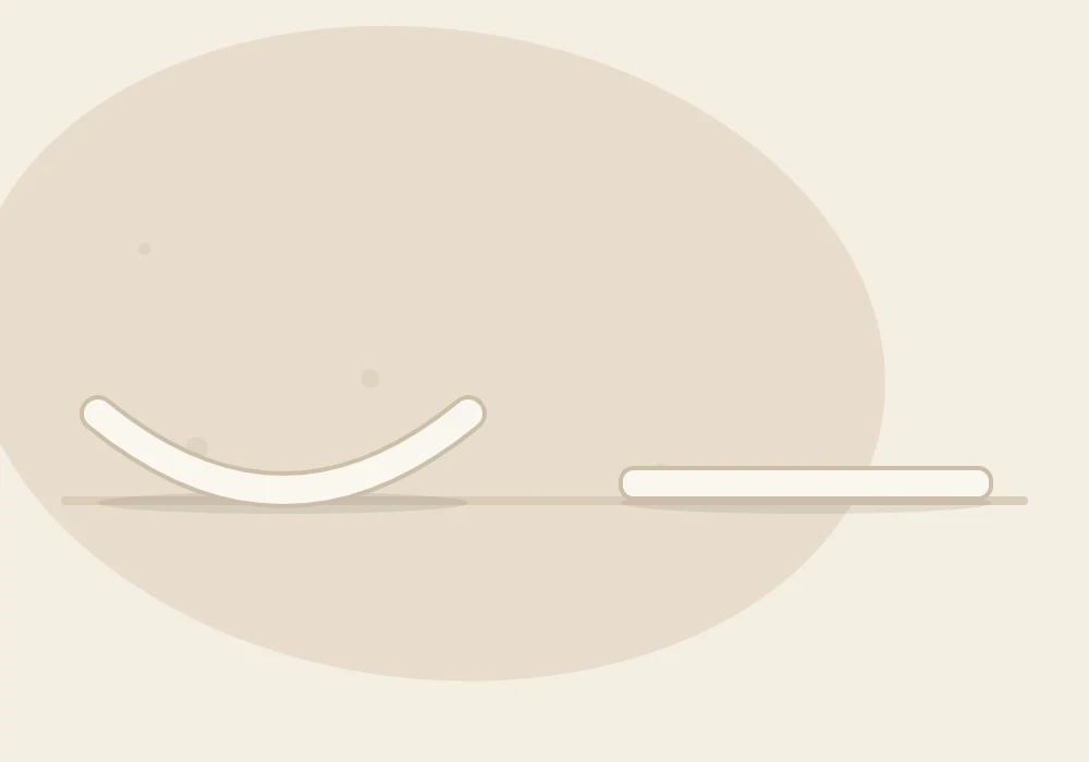 Side view of two flat clay pieces on a table line: one curled up at the edges, one lying perfectly flat