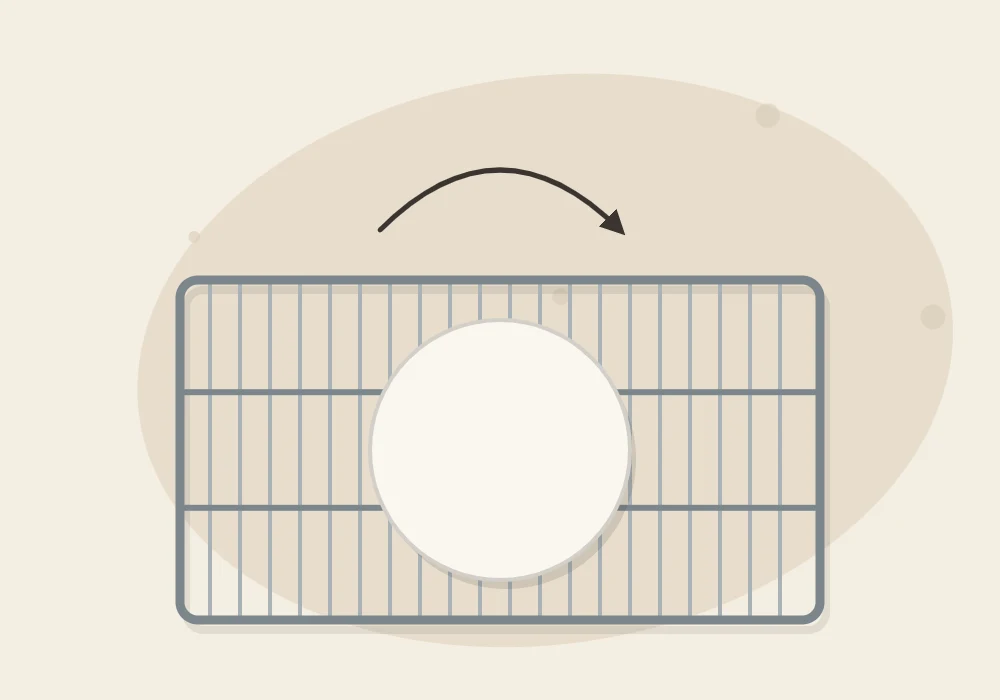 A flat clay disc on a wire rack with a curved arrow above it showing that the piece should be turned over while drying