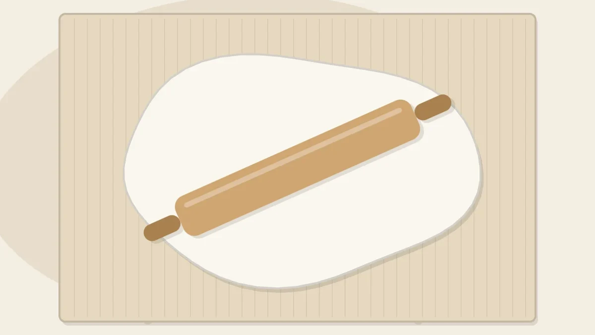 Top-down view of a wooden rolling pin lying across a freshly rolled slab of white clay on a canvas mat