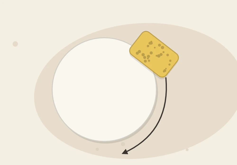 A sponge wiping along the rim of a clay disc, with a curved arrow following the edge